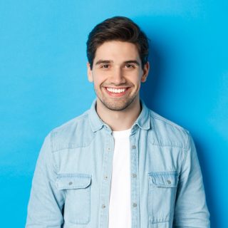 close-up-young-successful-man-smiling-camera-standing-casual-outfit-against-blue-background.jpg